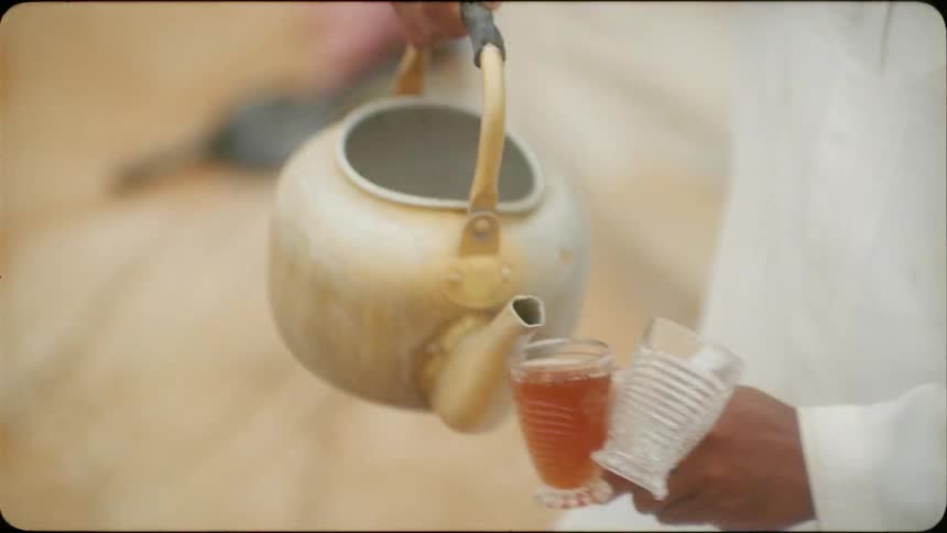 A man pours some tea from a kettle