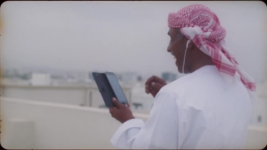 Man stands on a rooftop smiling and looking at a phone