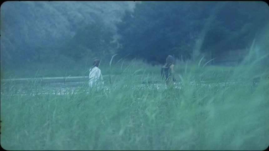 A man and woman wade across a river