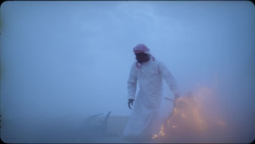 Man throws wood on a fire in the desert