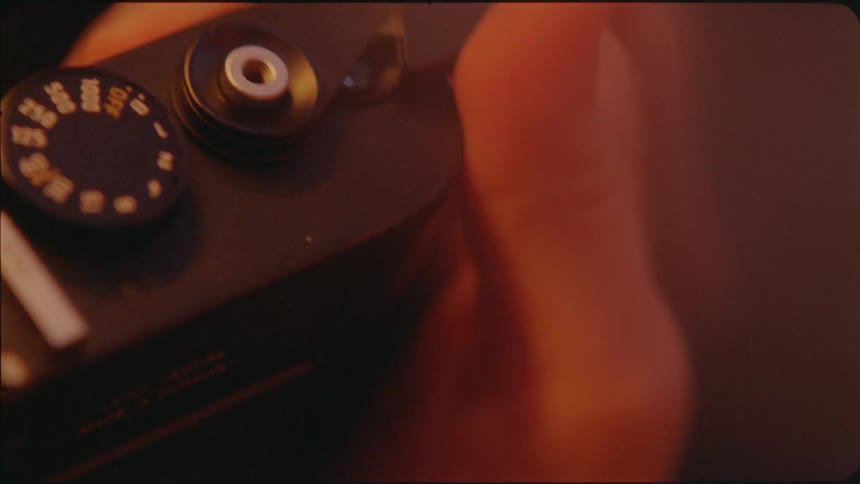 Thumb moves a lever on a camera then a finger pushes a button