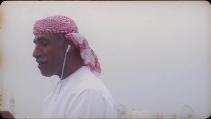 An arab man laughs as he talks to someone on the phone