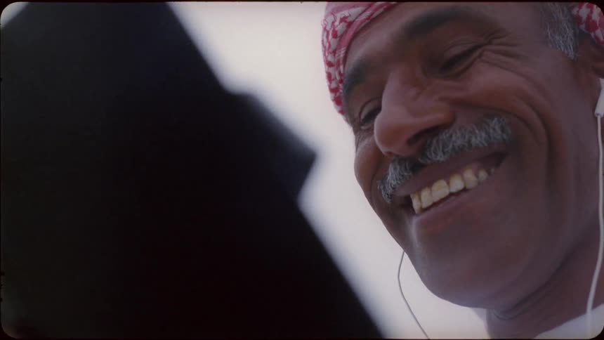 A man talks and laughs looking at a phone