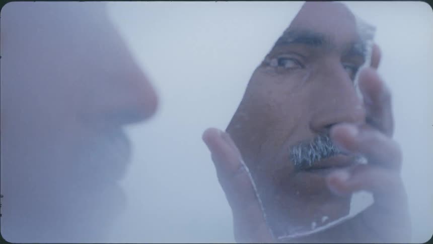 Man looks at himself in a shard of mirror