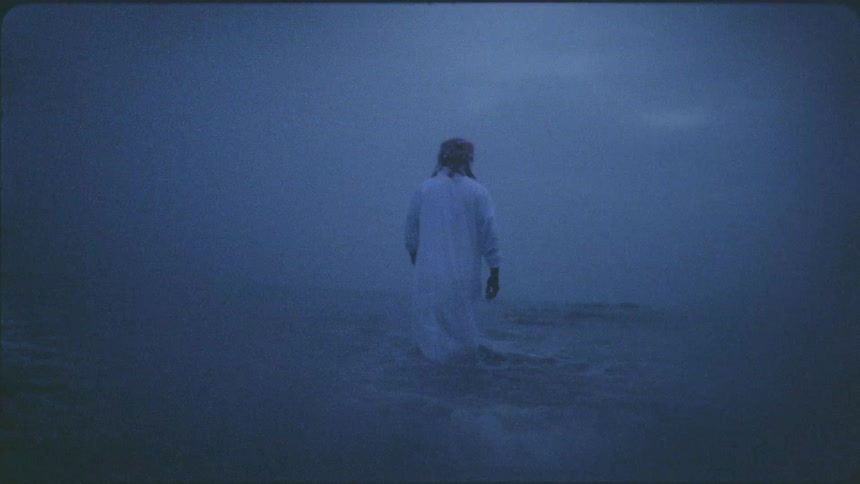 Man walks into a body of water in the evening