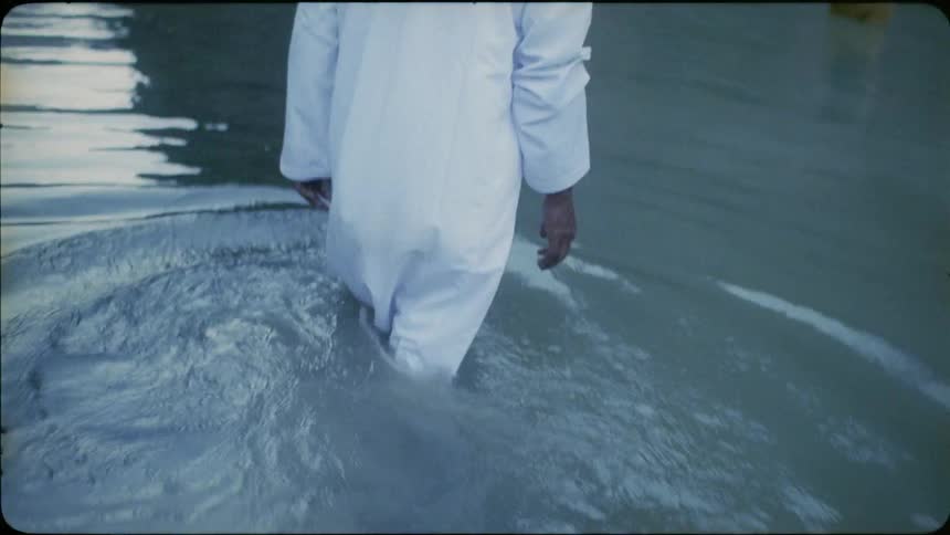 Man in a long gown walks in a lake