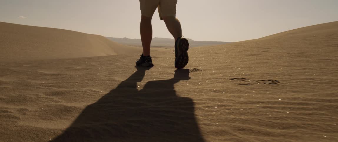 Man walks in the desert under the bright sun