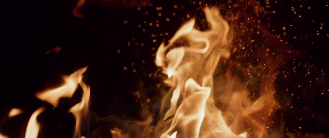 A fire burns outside at night