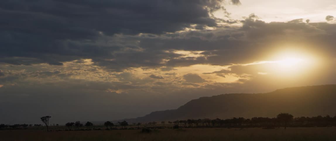 Clouds are drifting across a natural landscape at sunset