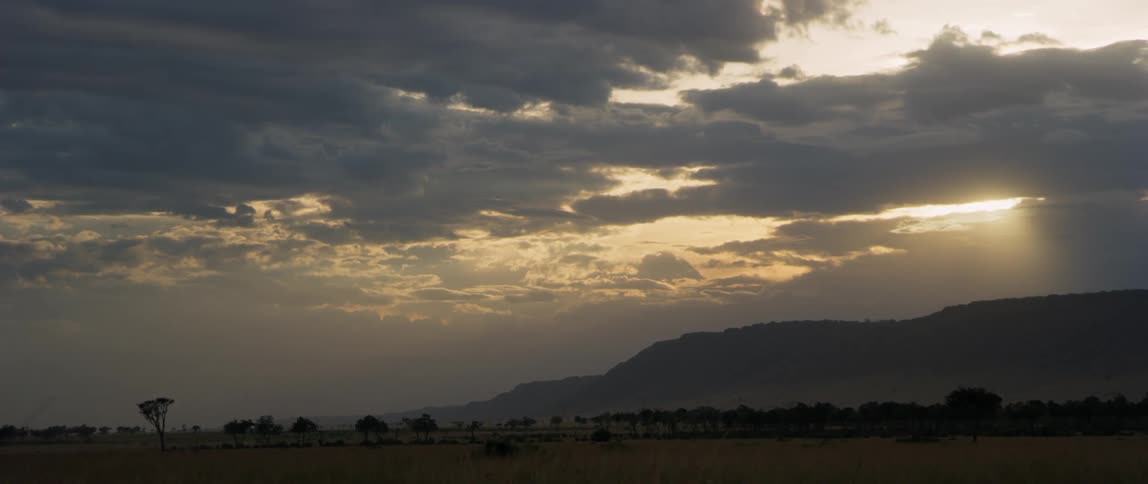 Clouds are drifting across a natural landscape at sunset