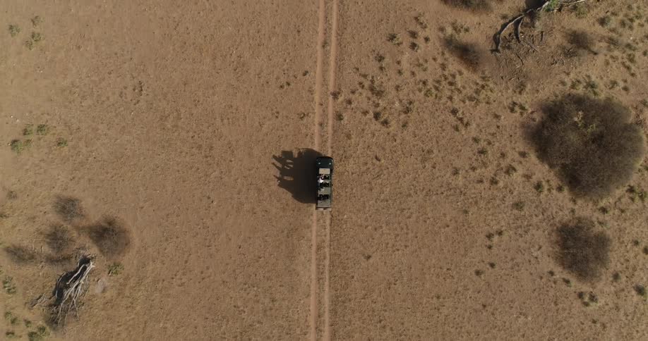 A vehicle drives across the flat desert