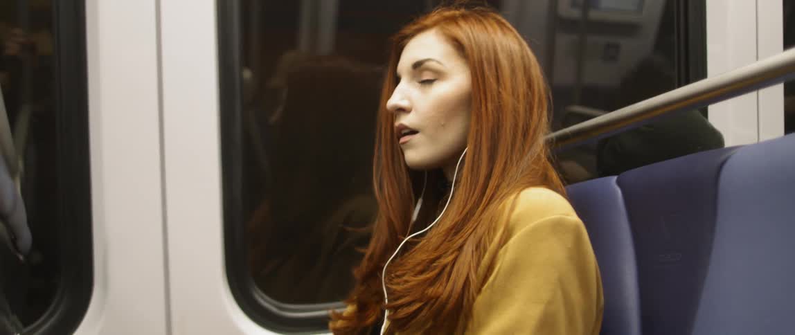 A woman puts on her earbuds in the train