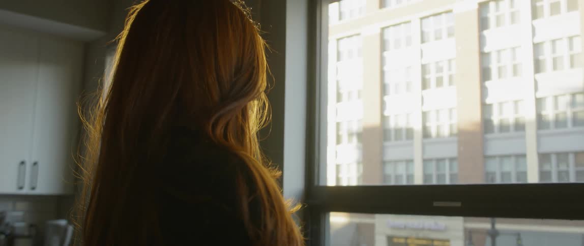 A woman looks out of an apartment window
