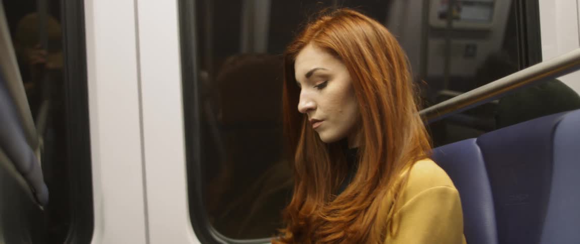 Woman sits in a train as it travels past lights