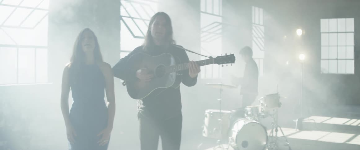 Man plays a guitar as he and a woman sing