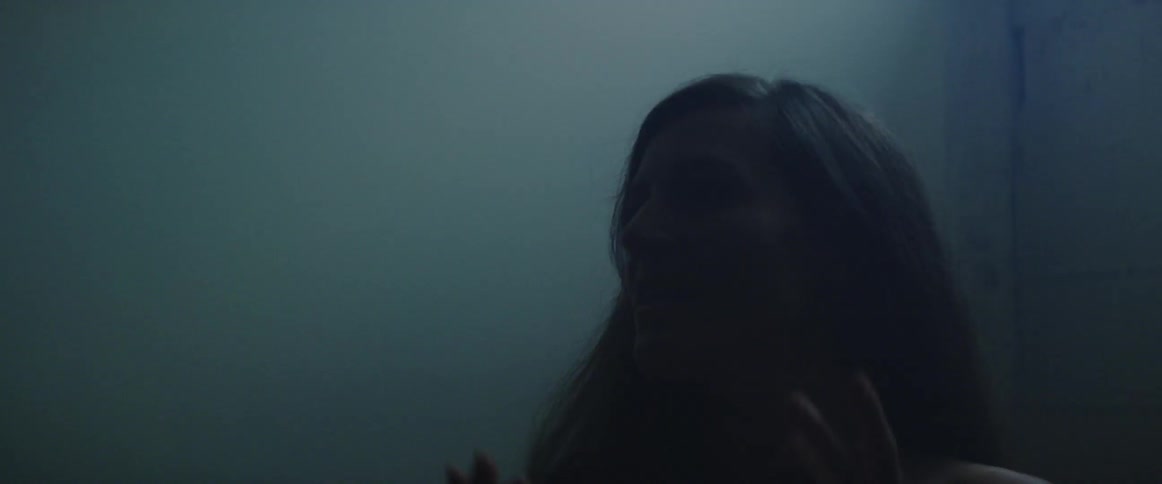 Woman standing outside in the fog waves her hands in the air