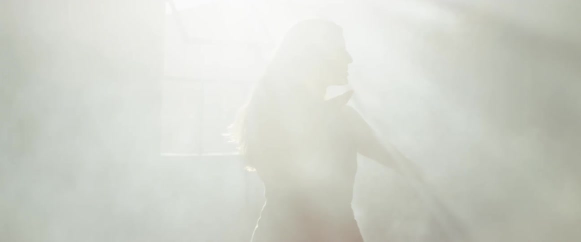 Woman moves her arms as she stands in the rays of the sun