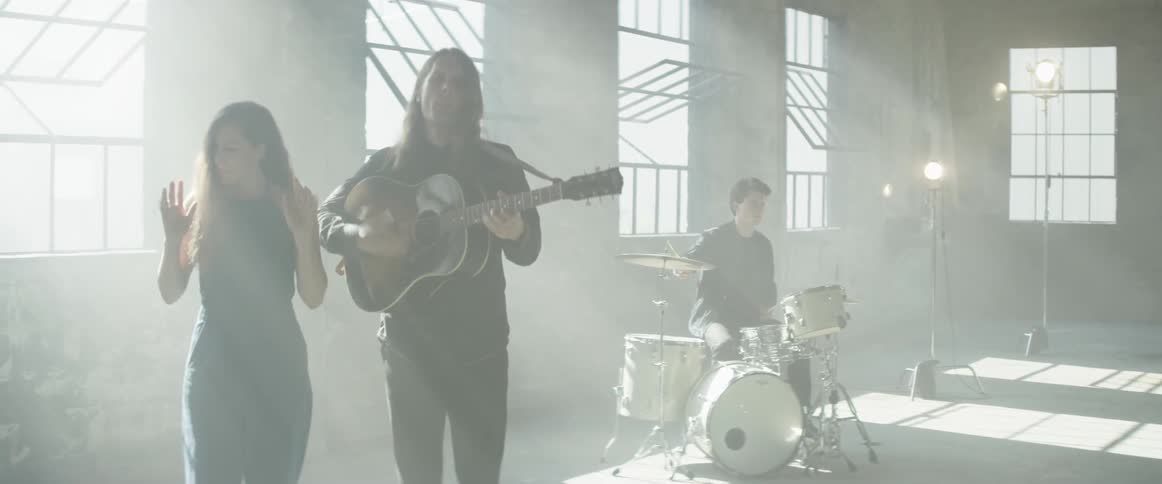 Man plays a guitar as he sings with a woman standing next to him