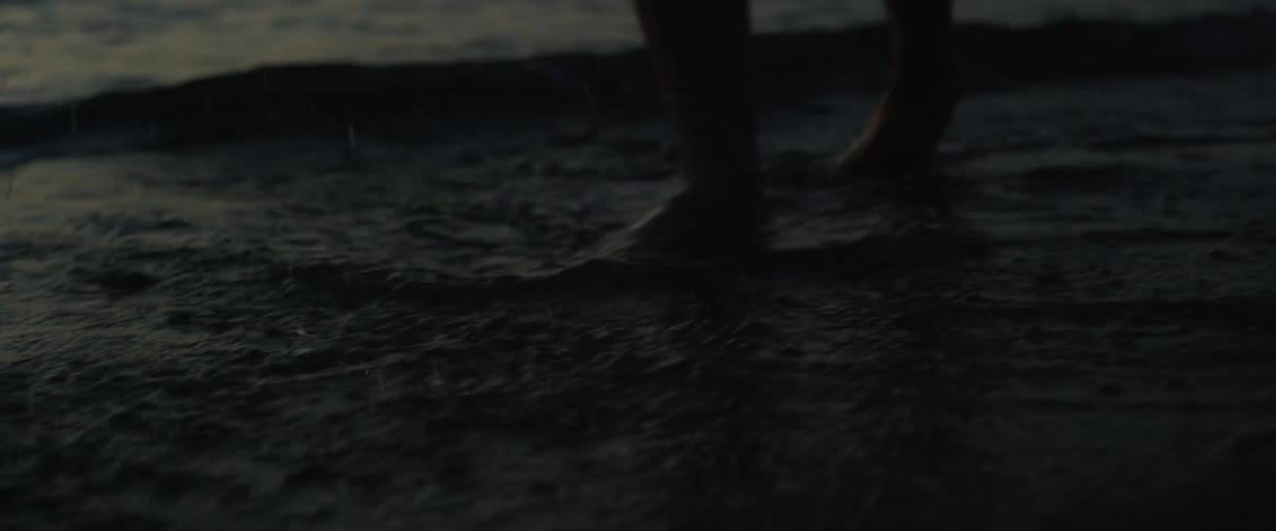 A person splashes their feet in the beach water