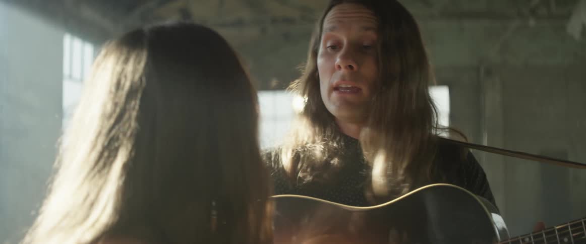 Man plays a guitar as he and a woman sing