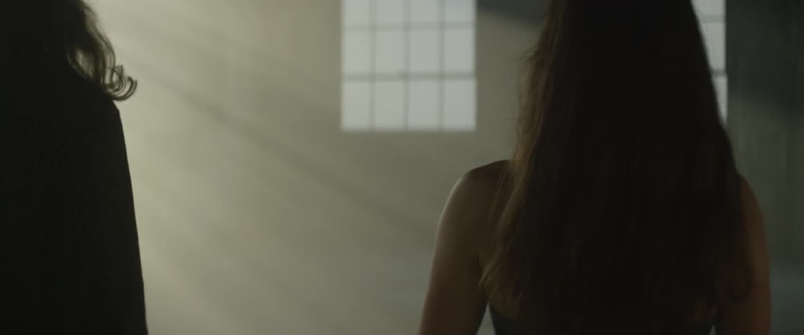Man and woman walk in a large room with sun streaming in the windows