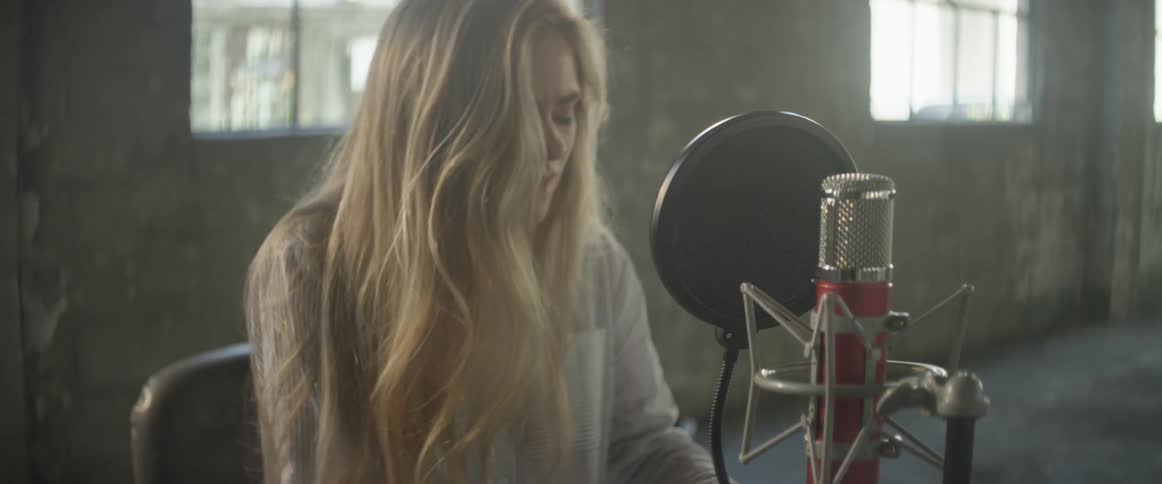 A woman sings into a recording microphone