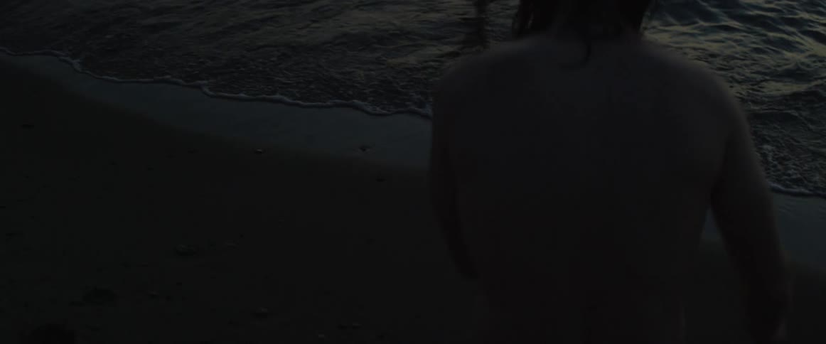 A man runs to the water to join a woman wading in the surf