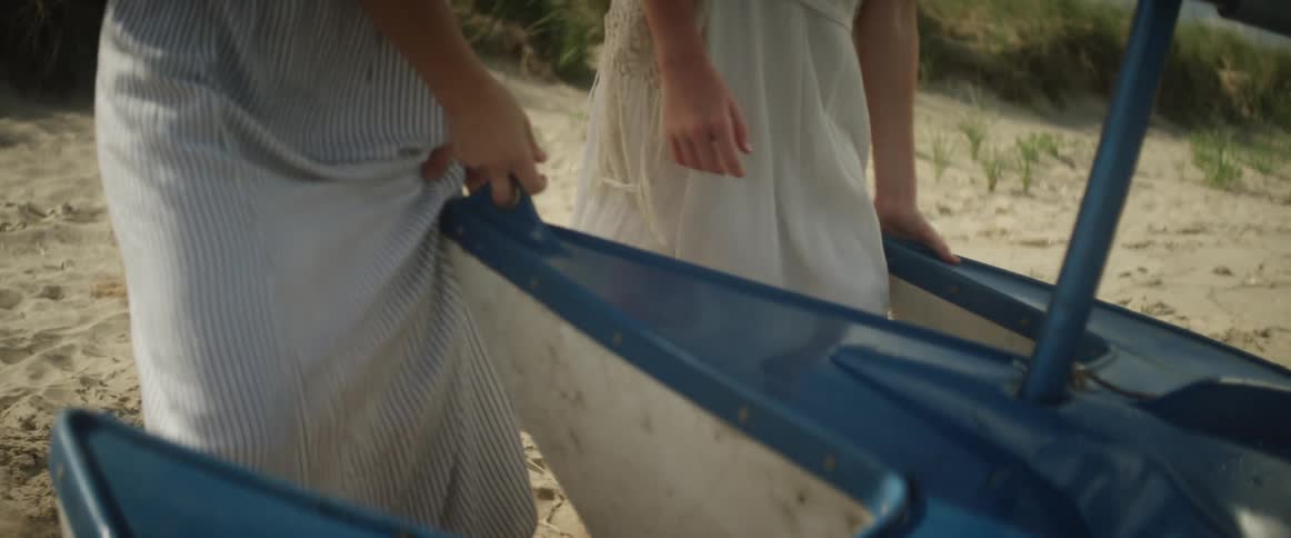 Two women are turning a boat in the sand