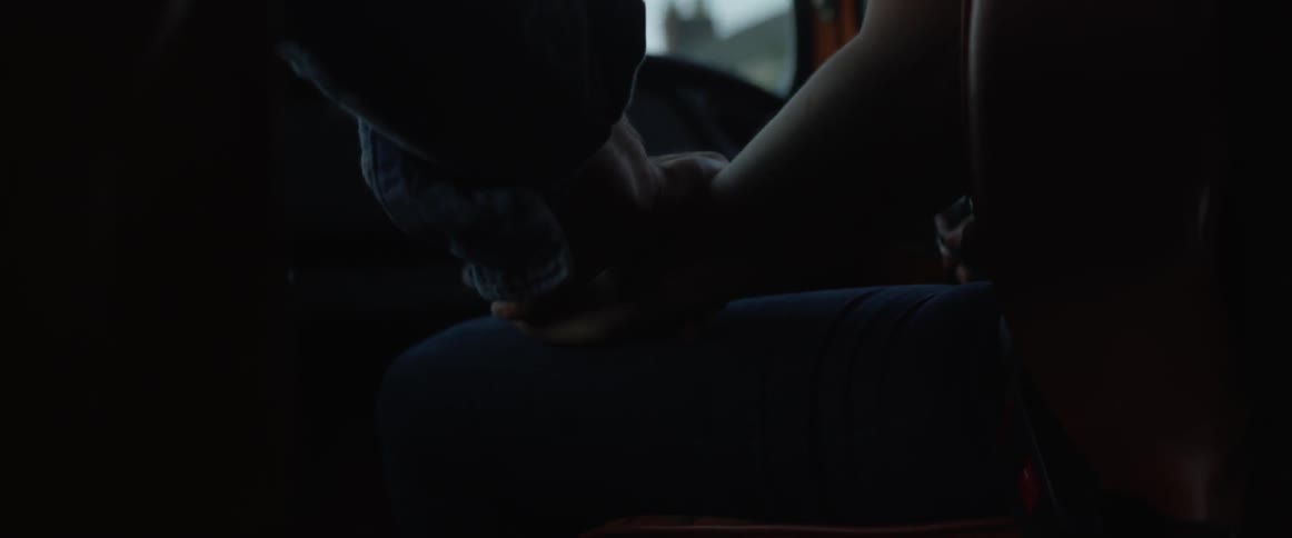 A man and woman hold hands in a car
