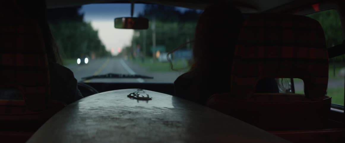 Two people drive down a country road in the evening
