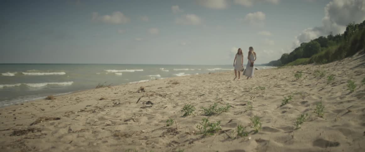 Two women walk on the beach near the ocean