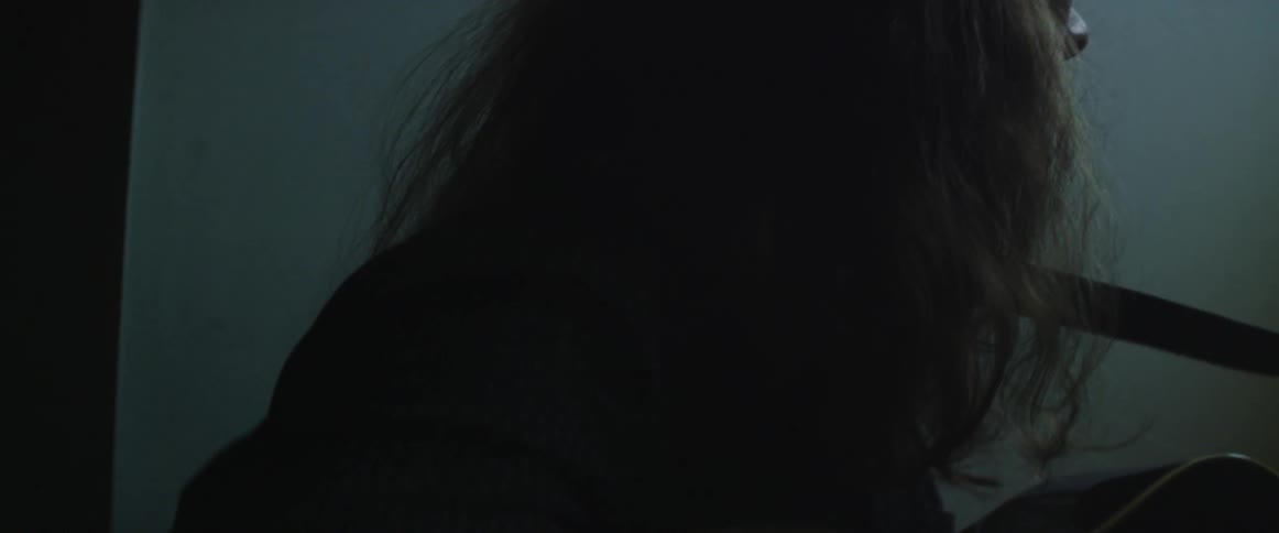 Woman sits outside in dim shadows