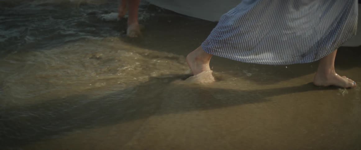 Two women push a small boat into a water
