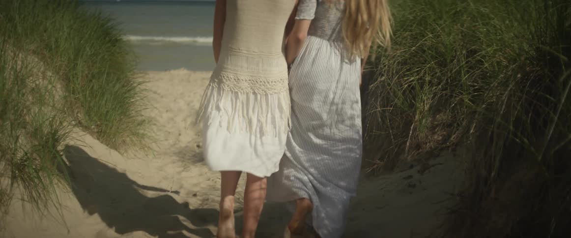 Two women walk on the beach near the ocean