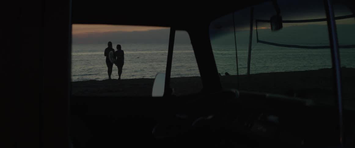 Two people walk towards the beach at dawn