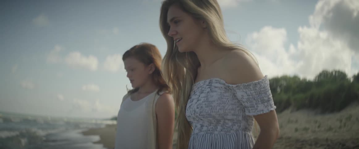 Two girls are walking towards the waves on a beach in daylight