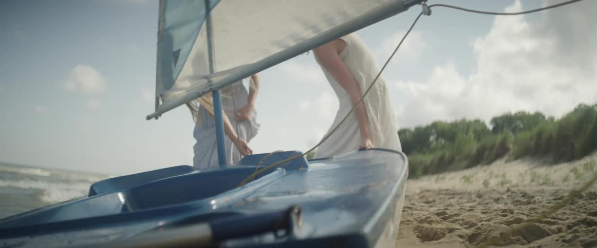 Two women pull a boat towards the water