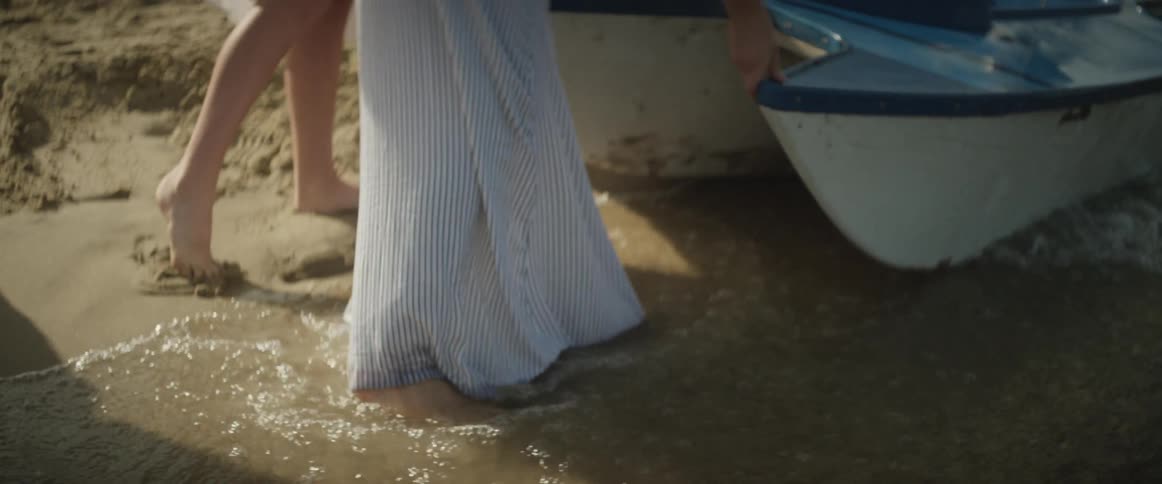 Waves roll in towards two people near a boat