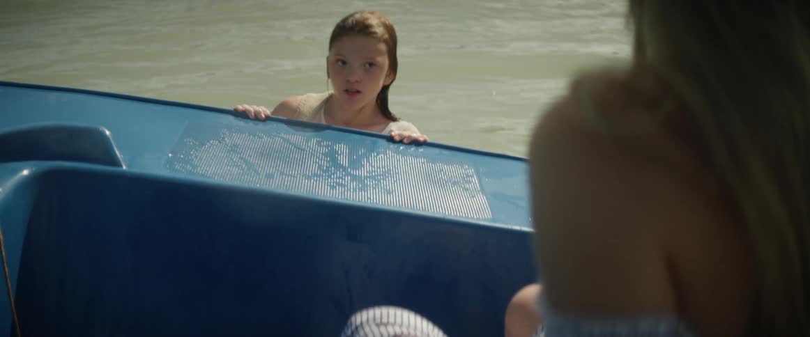 Child holding onto a small boat in the water