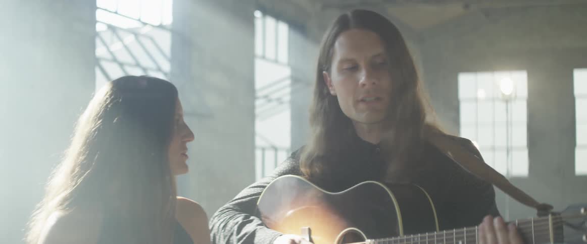 Man and woman sing and man strums a guitar