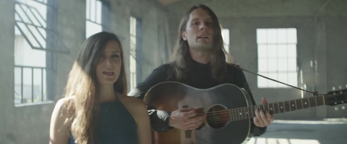 Man and woman sing and man strums a guitar