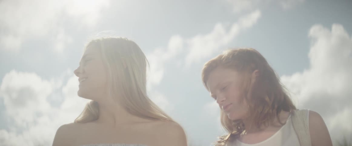 Two girls are standing outside in a natural landscape looking around