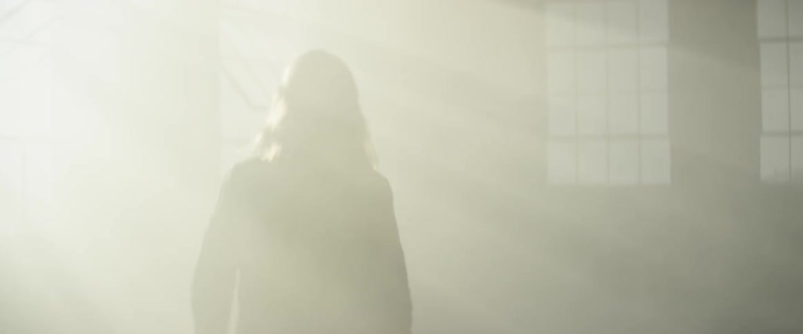 A woman walks through a room as the sun's rays shine through a window