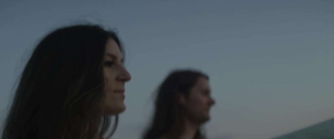 Man and woman stand outside at sunset
