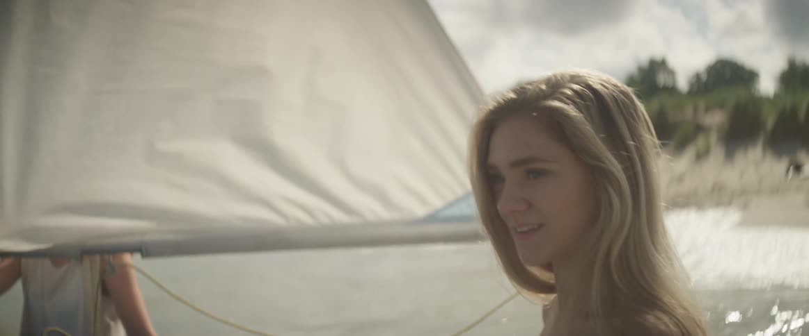 A woman sits on a sailboat on a sunny day