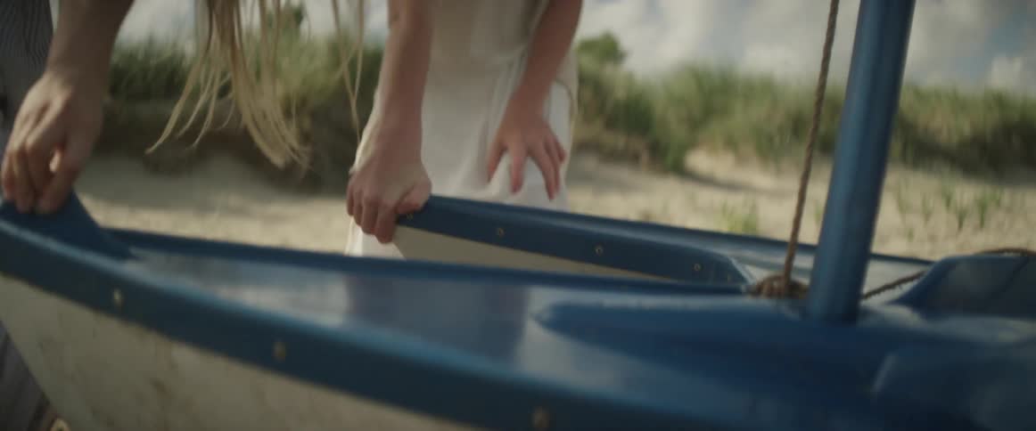 Two women pull a boat up onto the sand on a sunny day