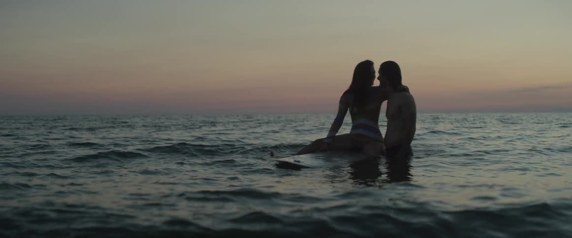 A man and woman hug in the ocean water