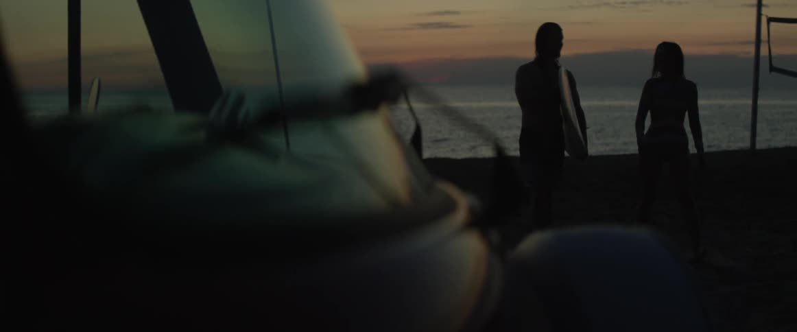 A man and woman walk towards the ocean water