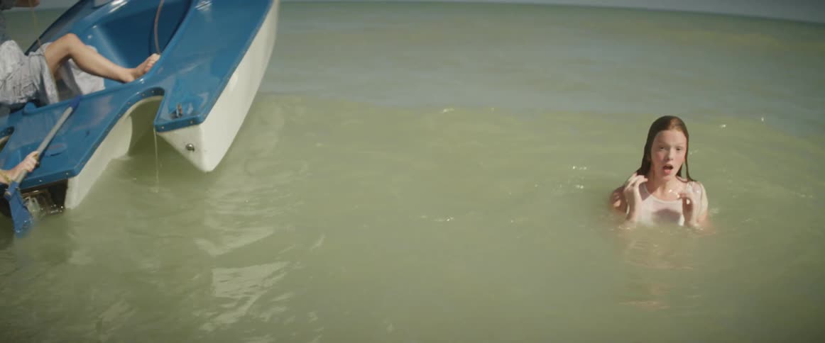 Person swims in the ocean next to a small blue boat