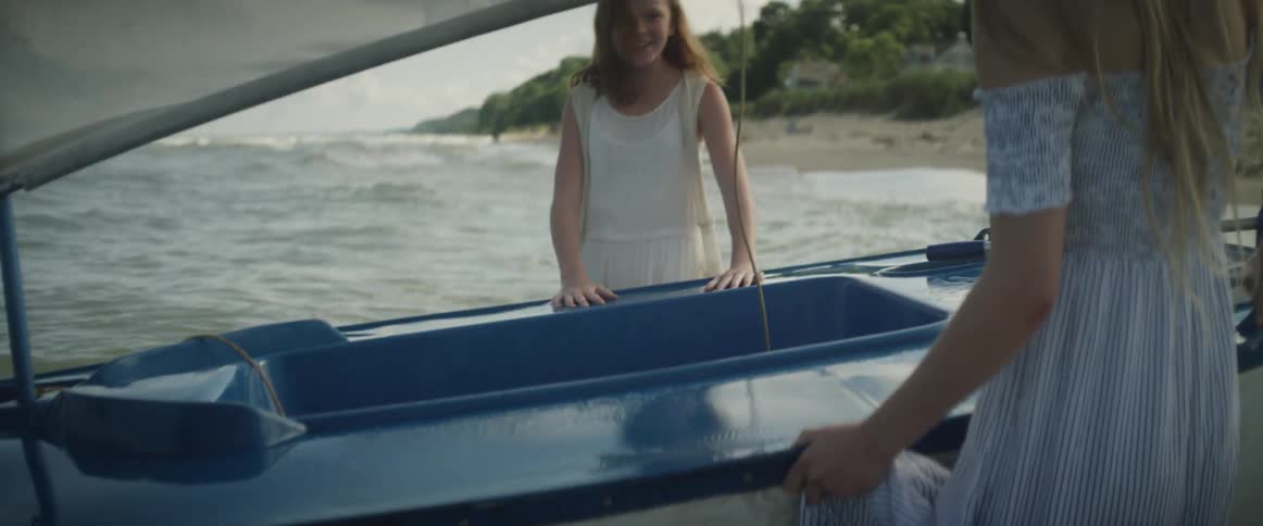 Woman and girl holding onto a small blue boat in the ocean